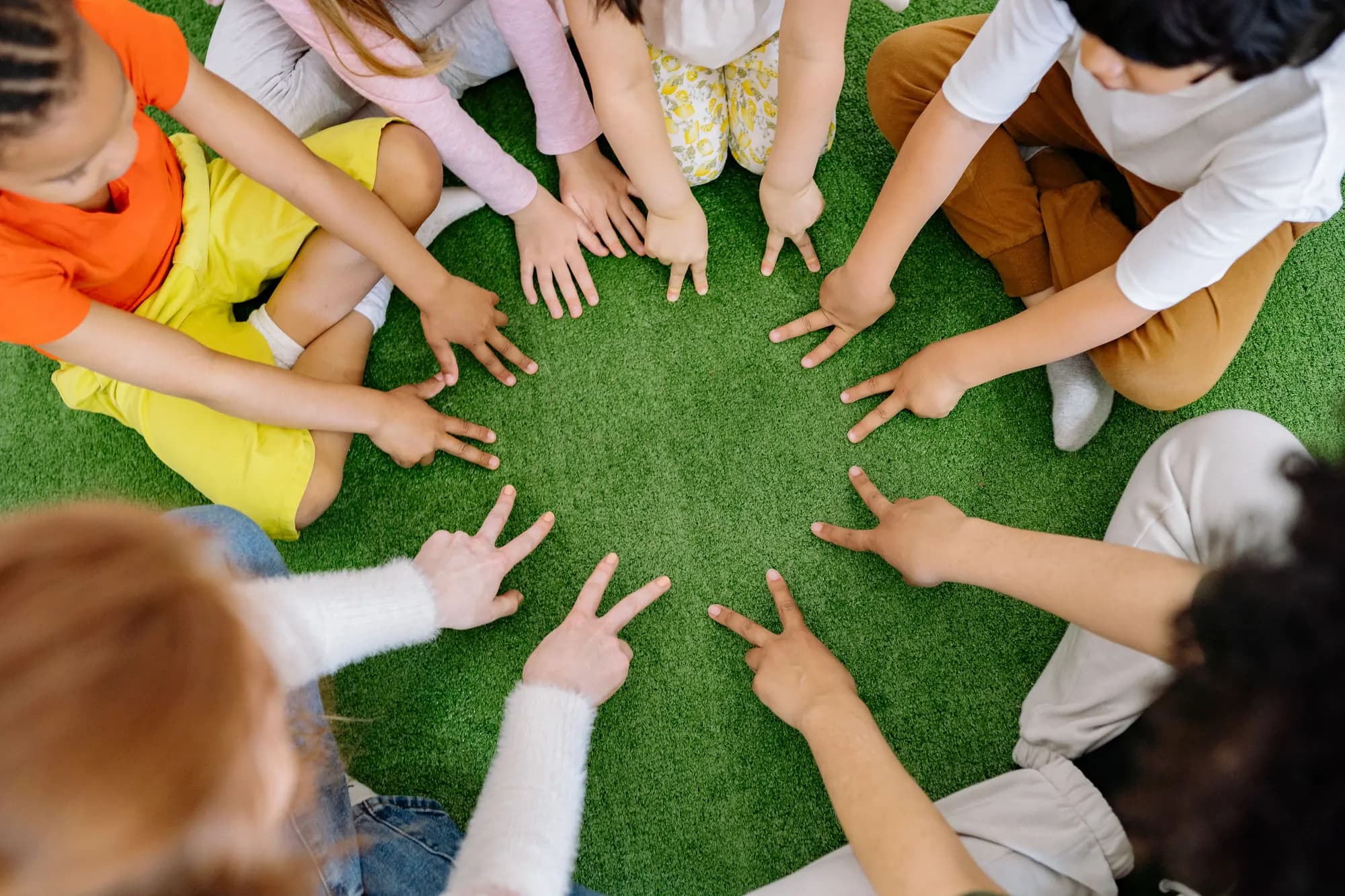 Children sitting in a circle on artificial grass