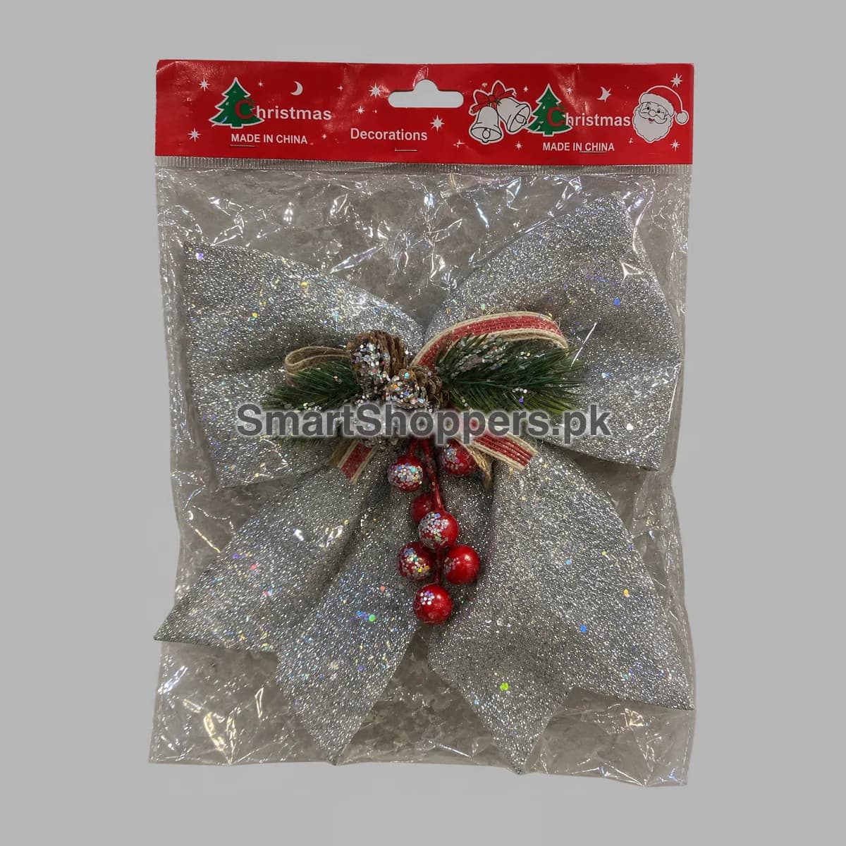Large silver glitter bow with pine sprigs, pine cones, red berries and red ribbon, in its bag